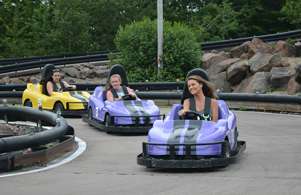 Three girls smiling and racing on go-karts