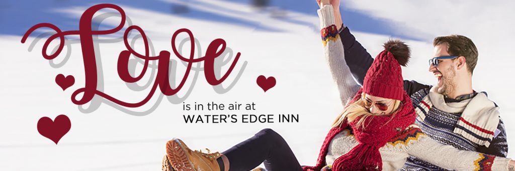 A couple on a sled laughing with love is in the air at water's edge in written next to them