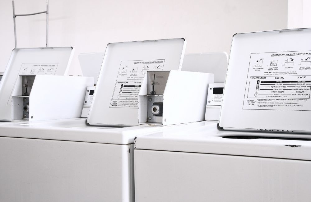 Three white coin operated washing machines