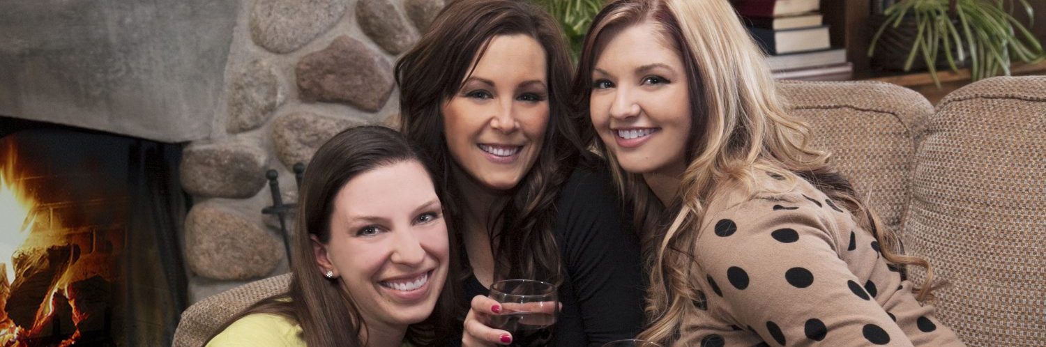 Three friends smiling in front of a fireplace