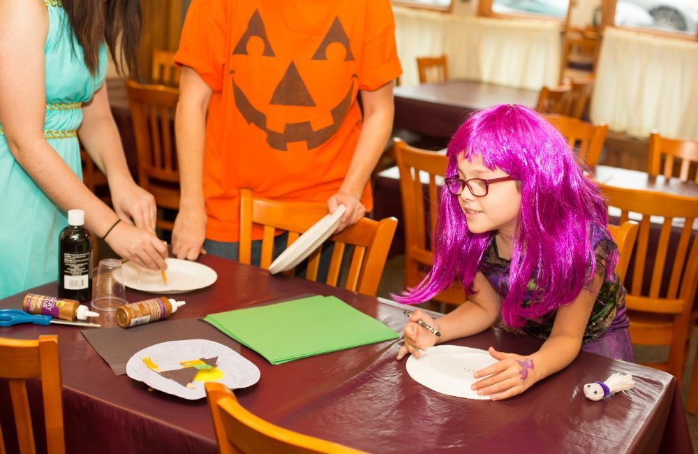 A little girl in a halloween costume doing crafts