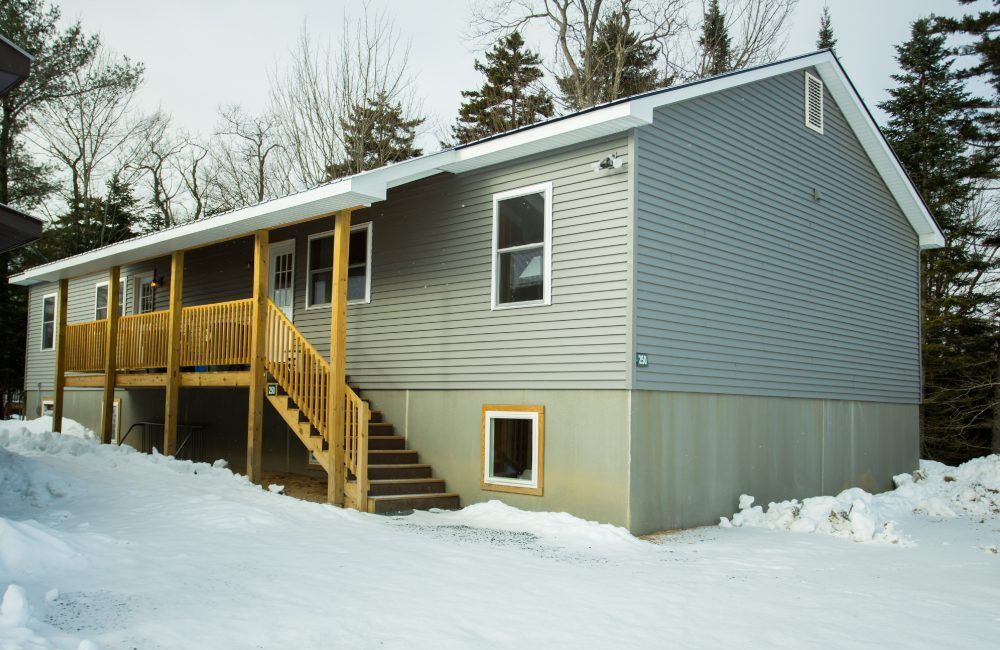 A grey house in winter with a wooden front porch