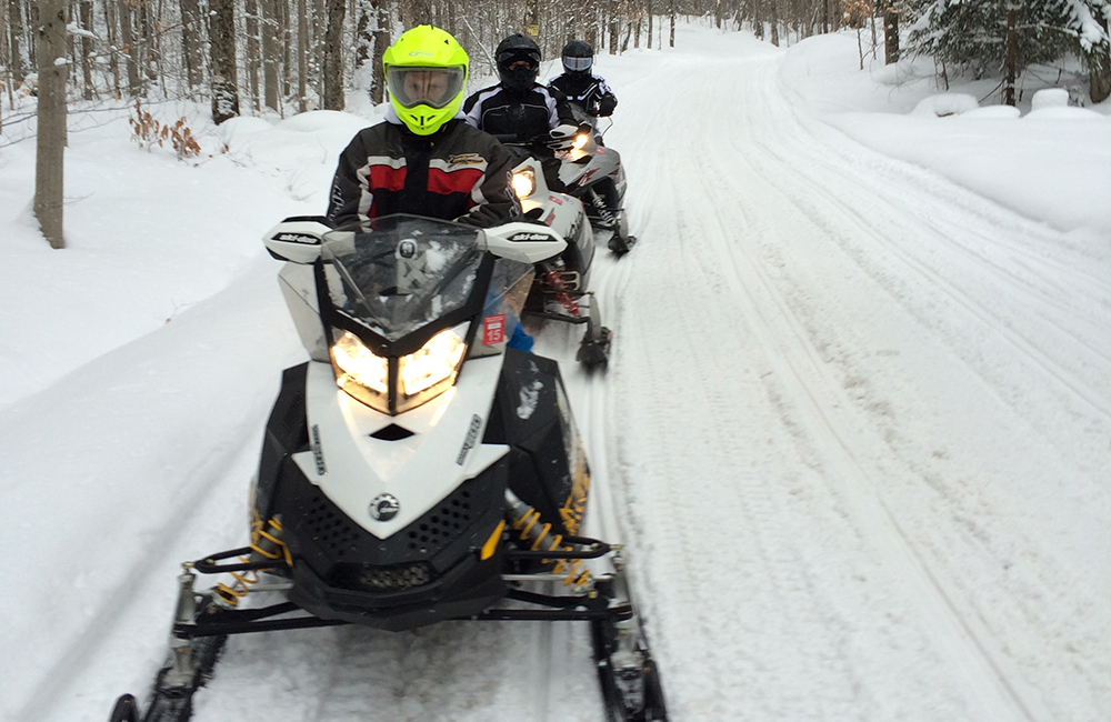 Three people on snowmobiling on a trail