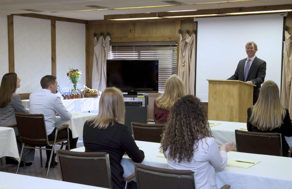 A business man speaking at a podium to other business people