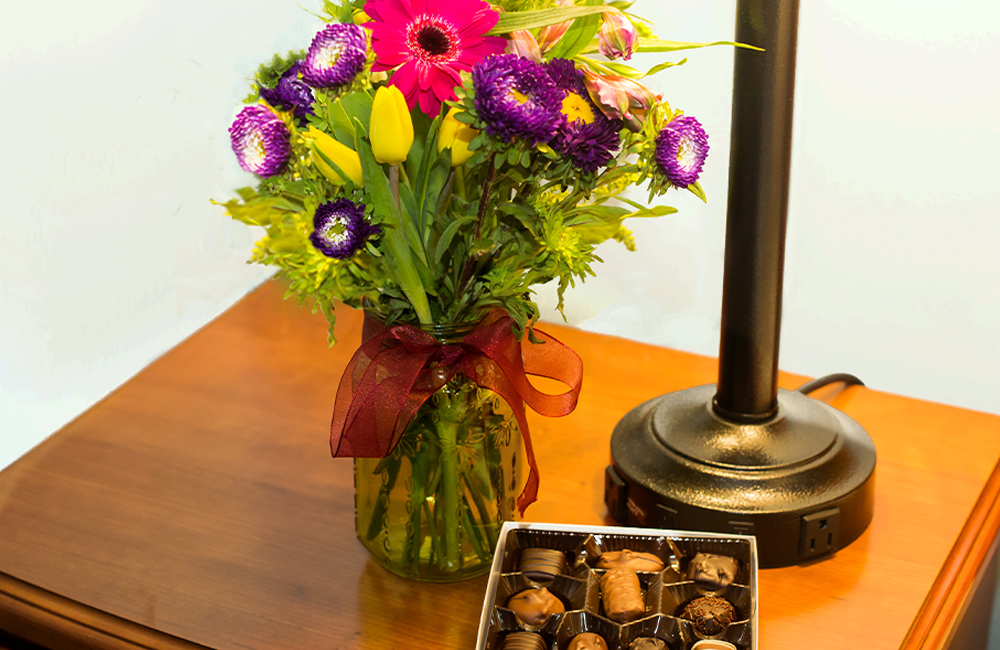 Vase of flowers and chocolate on a nightstand