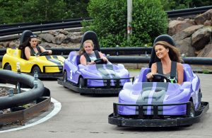 Three girls smiling and racing on go karts