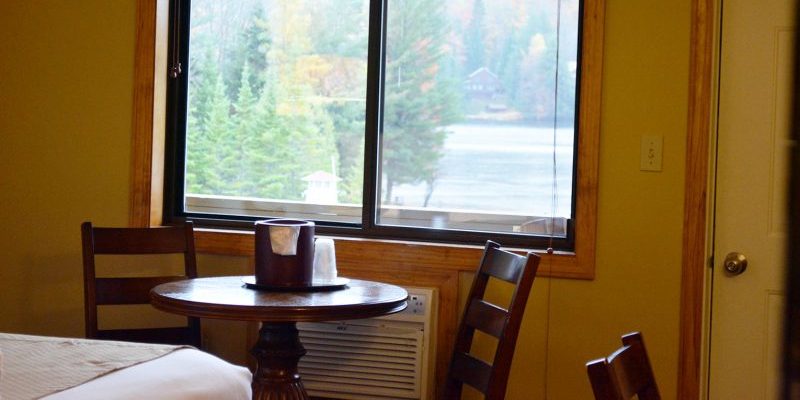 A small table with two chairs next too a window with a lake view