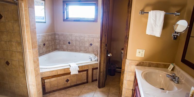 A bathroom with a separate shower and tub, and toilet with a door that closes, and a double sink