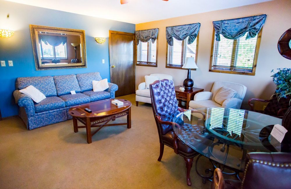 A living room with a couch, coffee table, two chairs, a stand with a lamp, and a table with chairs around it