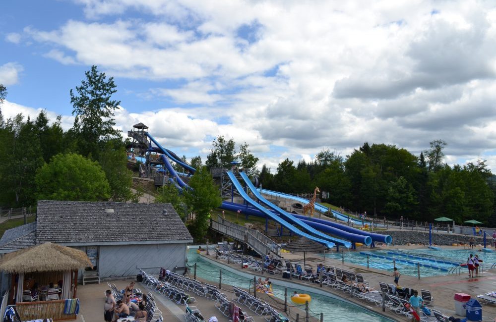 Large water slides, pools, and pool chairs with people walking around at water safari