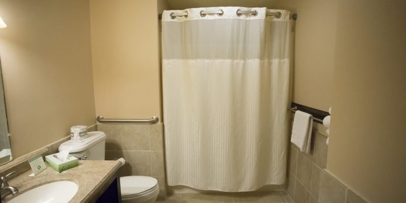 A bathroom with a white toilet, a bathtub with a shower curtain, a sink, and a sink