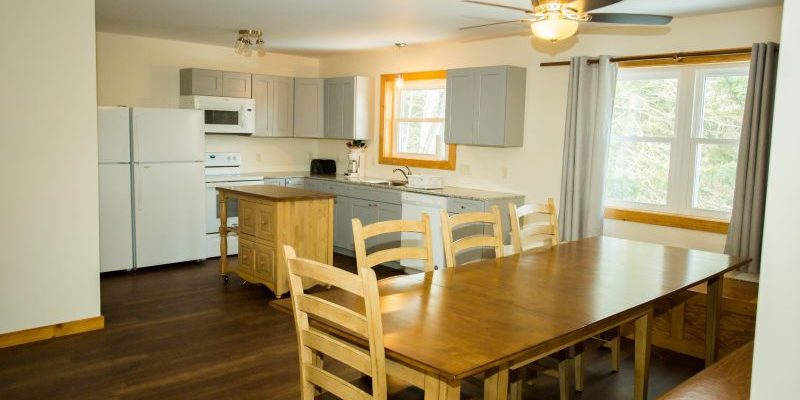 A kitchen with full appliances and a long wooden dining room table