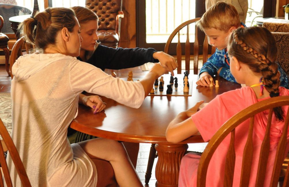 a family at the table and the kids are playing chess