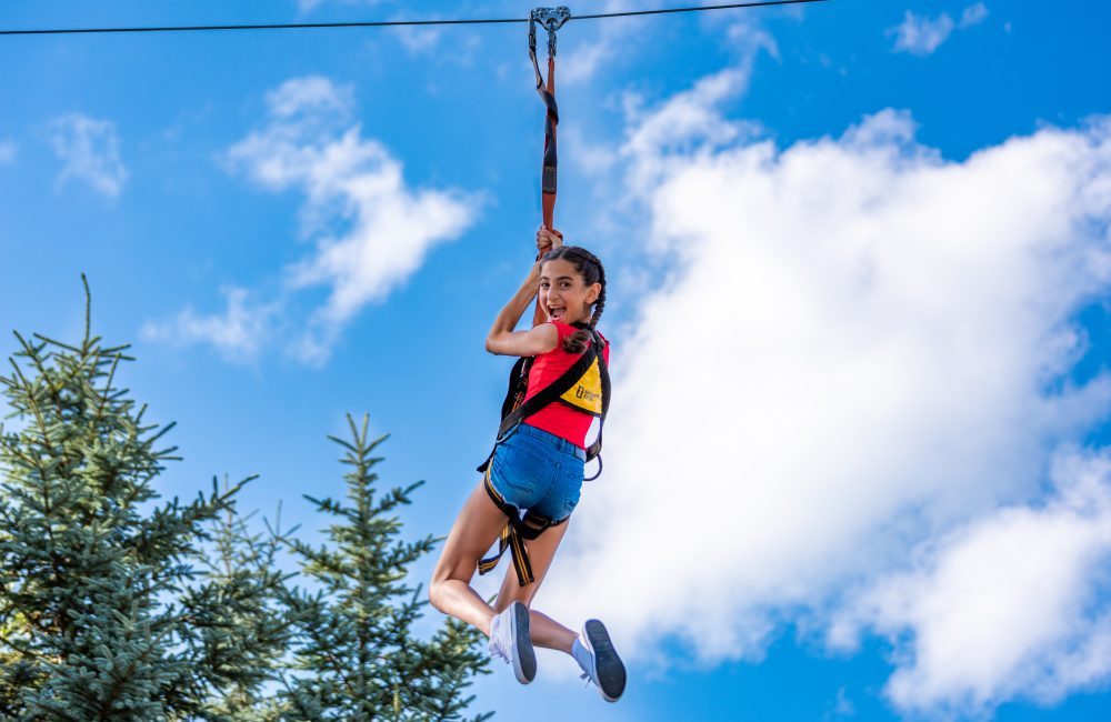 A girl smiling and hanging on a zipline