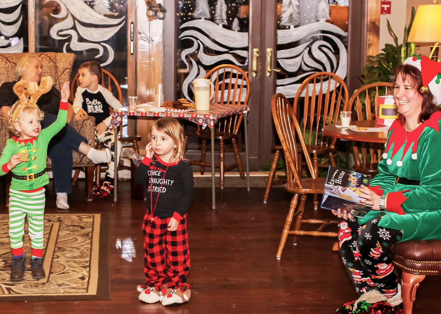 a woman smiling and wearing an elf costume and little kids playing in front of her