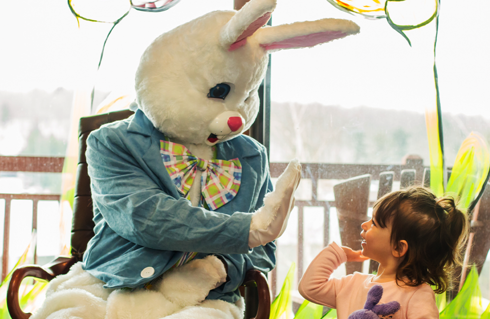 a little girl smiling and giving a high five to the easter bunny