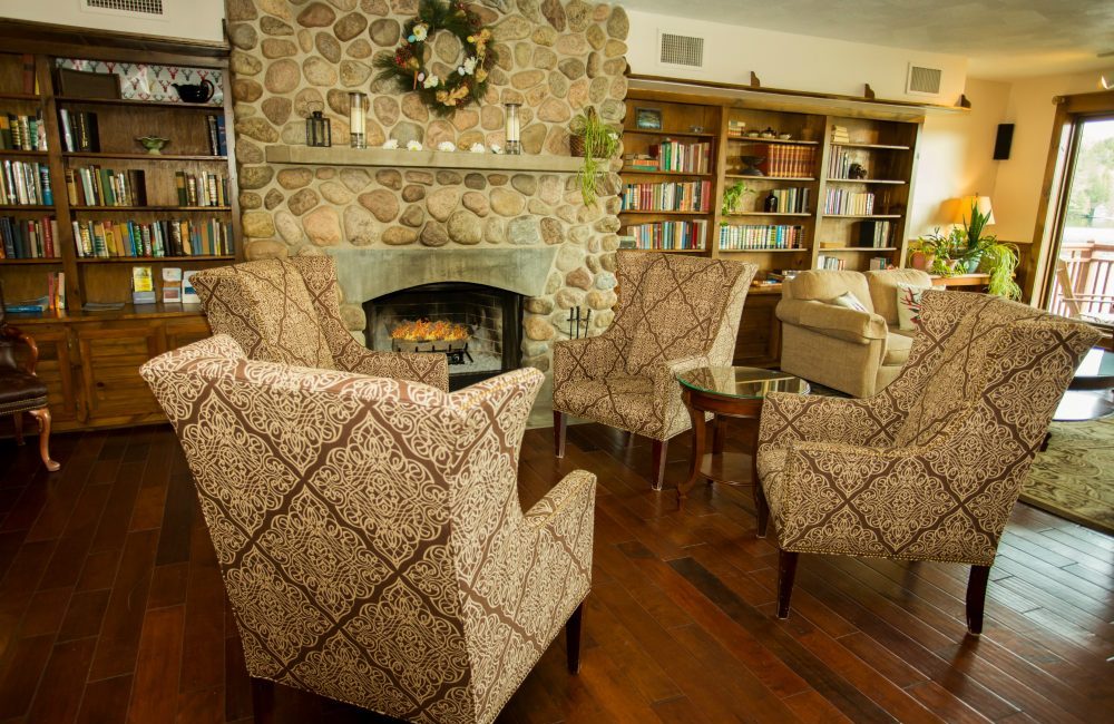 4 chairs set up infant of a stone fireplace with a roaring fire inside